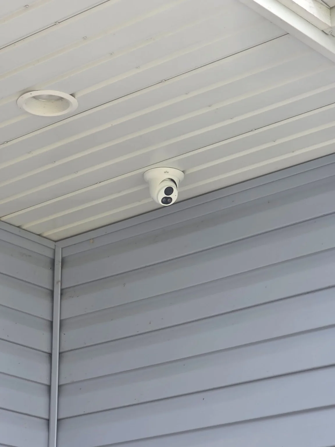 Close view of a Uniview security camera mounted under a home soffit